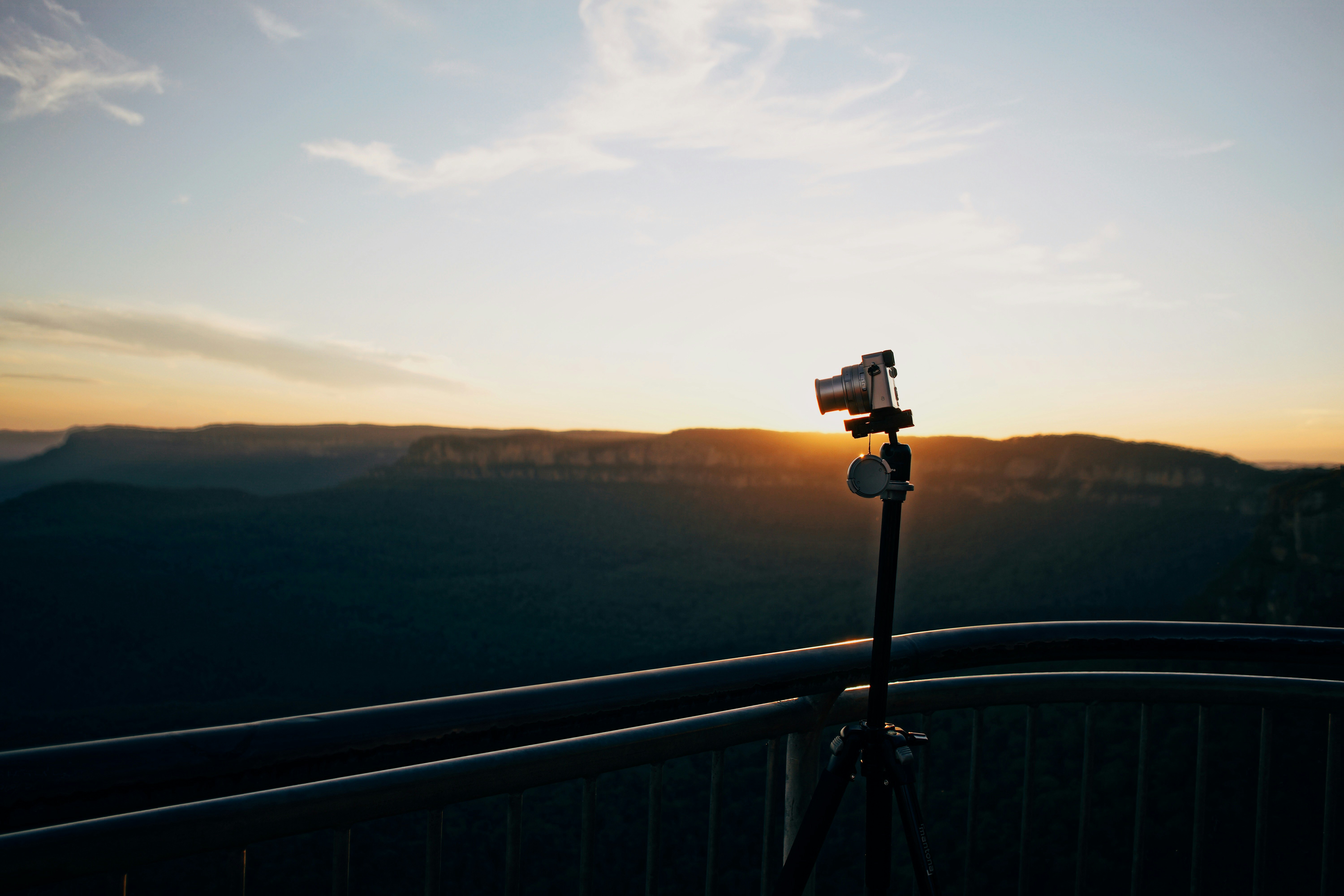 gray DSLR camera on tripod near railing